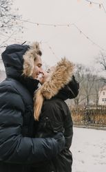 Smiling couple having fun on street near tree with fairy lights