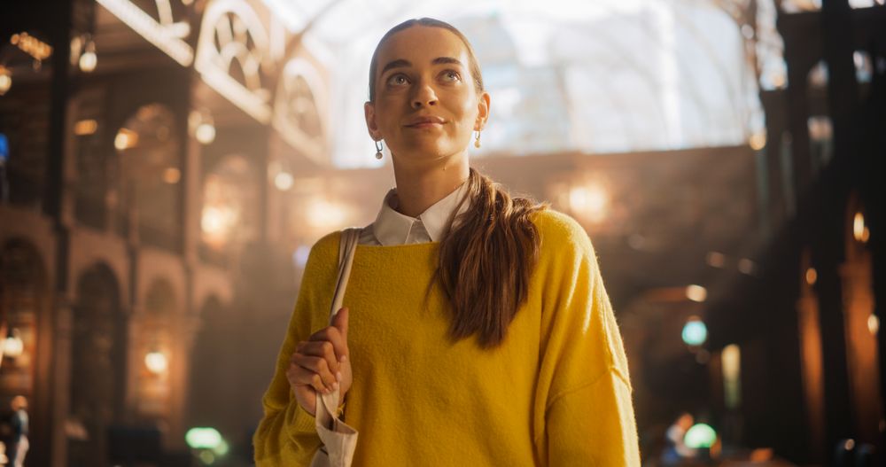 Young Woman in a Yellow Sweater Contemplating in a Historic Library