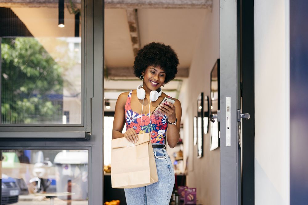 Black woman leaving cafe with brown bag