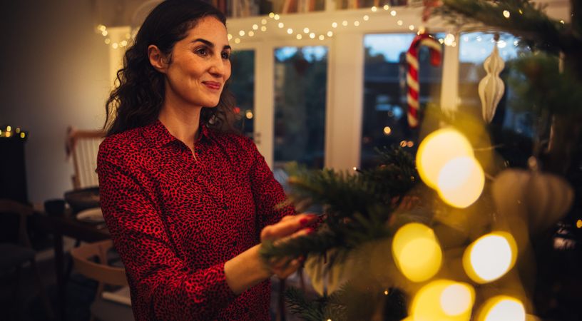 Woman placing decorative items on Christmas tree