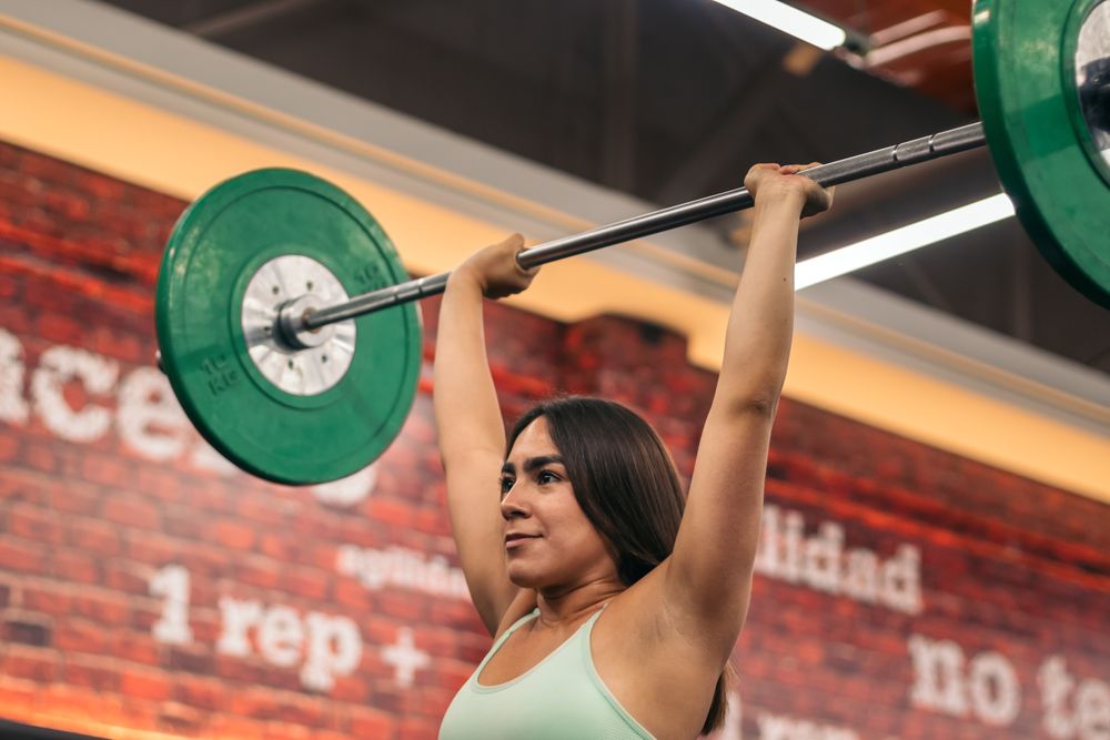 determined female athlete lifting barbell during weightlifting workout in gym while looking away