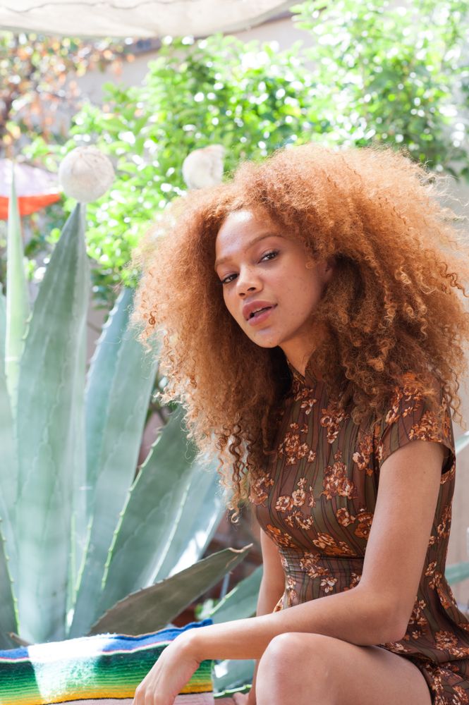 Portrait of young woman with afro tilting head looking at camera