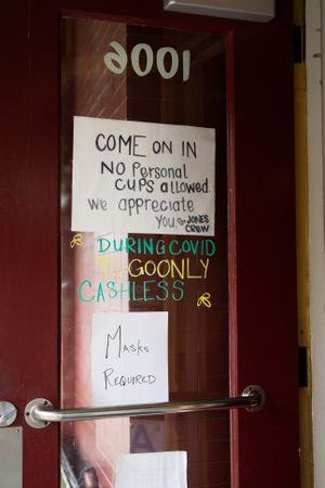 Handwritten signs on coffee shop door with coronavirus restrictions