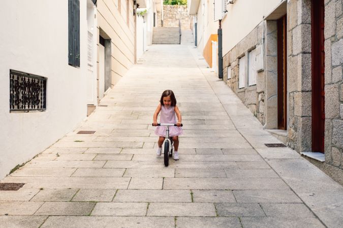 Girl riding on bicycle in narrow street
