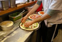 Pizza man adding ingredients to pizza
