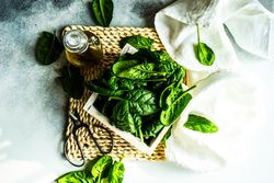 Top view of box of spinach leaves on rattan placemat