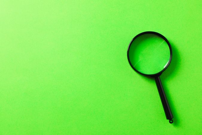 Magnifier on green background, space for text