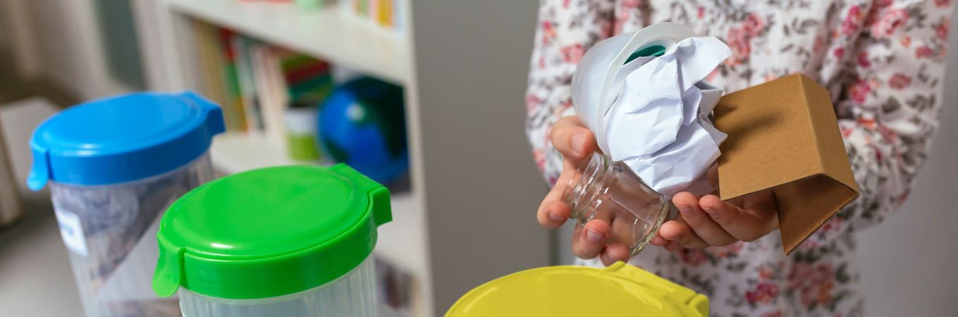 Girl in ecology classroom showing handful of waste to recycle