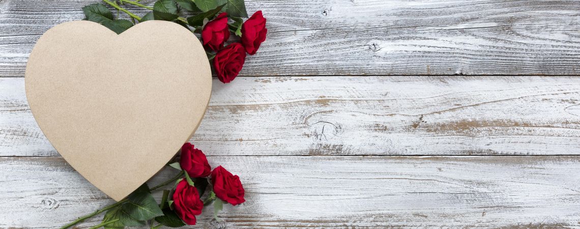 Happy Valentine’s Day with heart shape gift box and red roses on aged wood