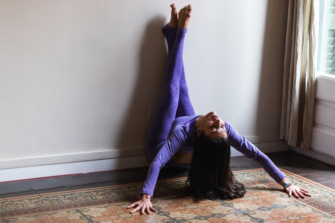 Peaceful young woman with closed eyes practicing yoga at home