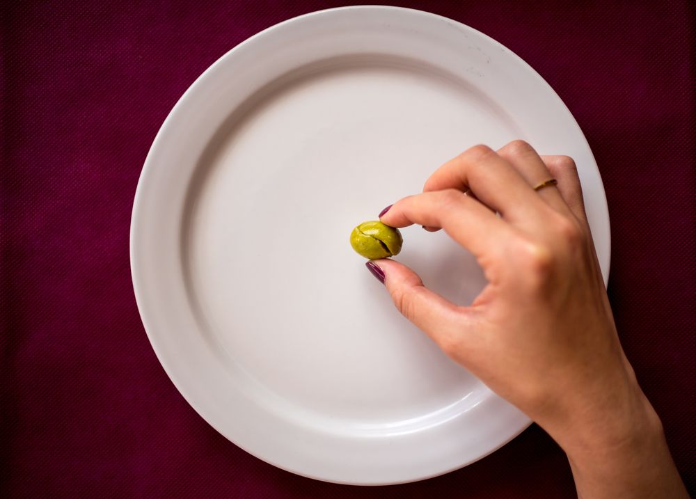 Faceless woman eating olive in restaurant