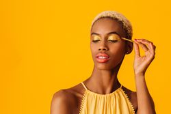 Black woman with short blonde hair applying eyeshadow