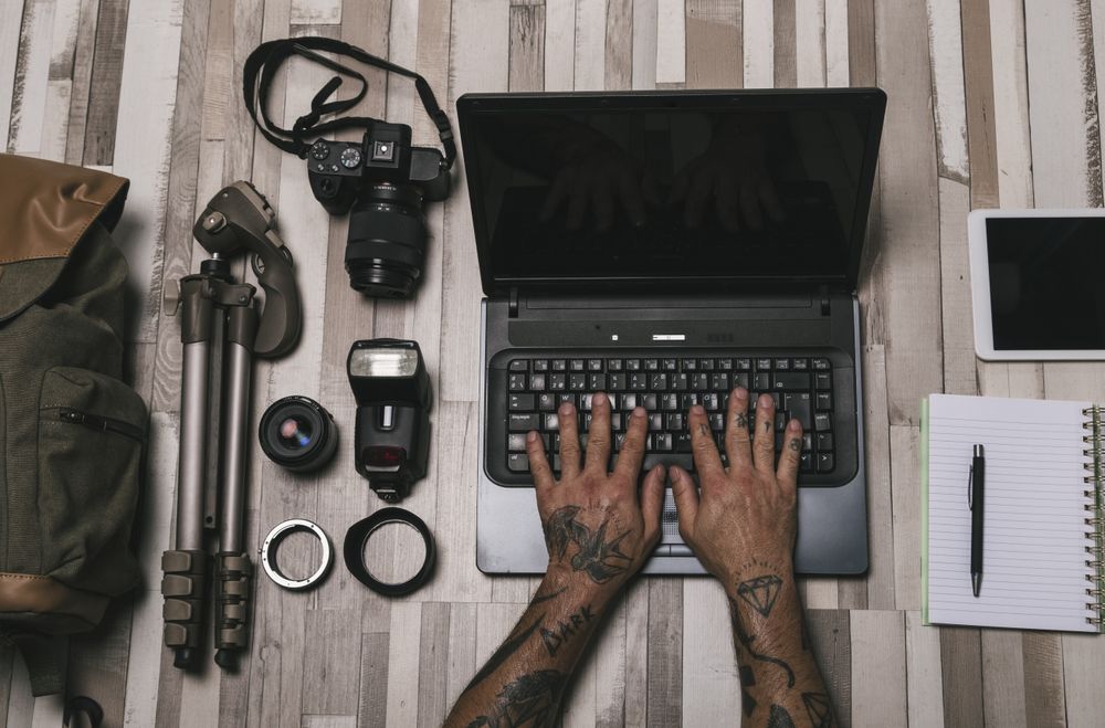 Anonymous photographer using laptop near equipment and stationery