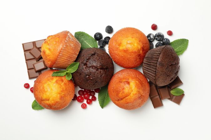 Muffins, berries and chocolate on studio background, top view