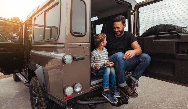 Man with little boy holding digital tablet while on road trip