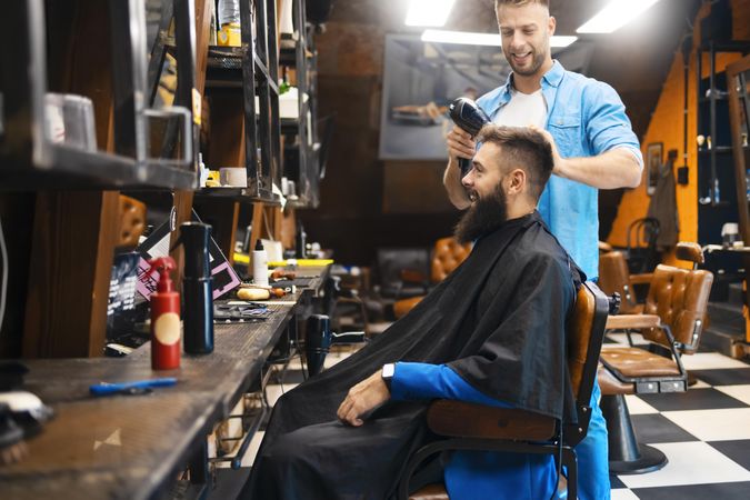 Barber blowdrying his client’s hair in salon