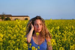 Dreamy woman in touching hair amidst tender yellow flowers