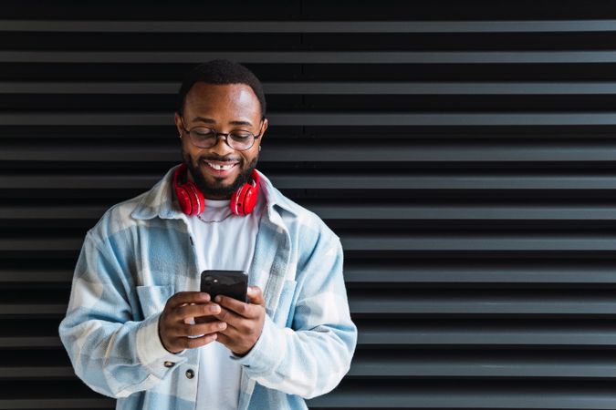 Cheerful Black man with smartphone listening to music