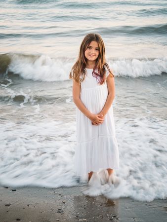 Smiling girl standing on seaside among waves