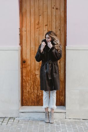 Stylish woman standing near brown door