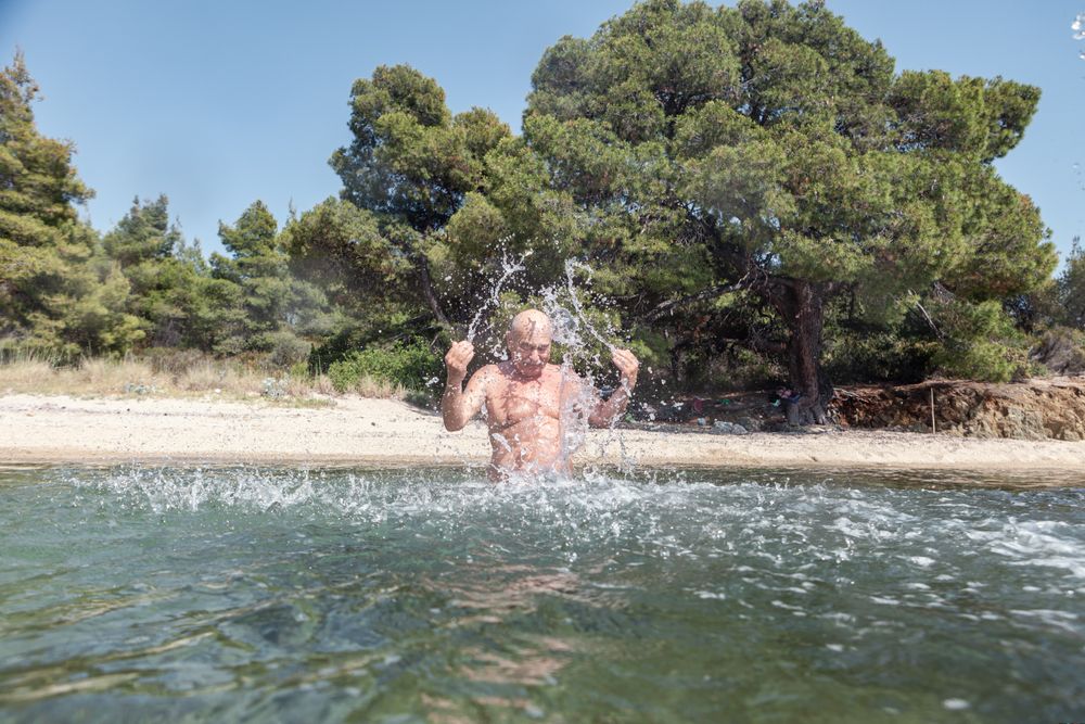 Man swimming and splashing water in sunlight