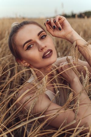 Portrait of blonde woman with purple lipsticks in wheat field