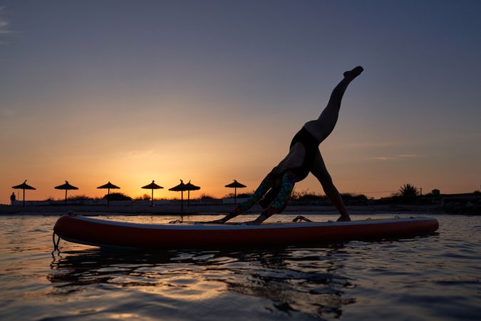 Silhouette of female athlete taking Downward Facing Dog pose on
