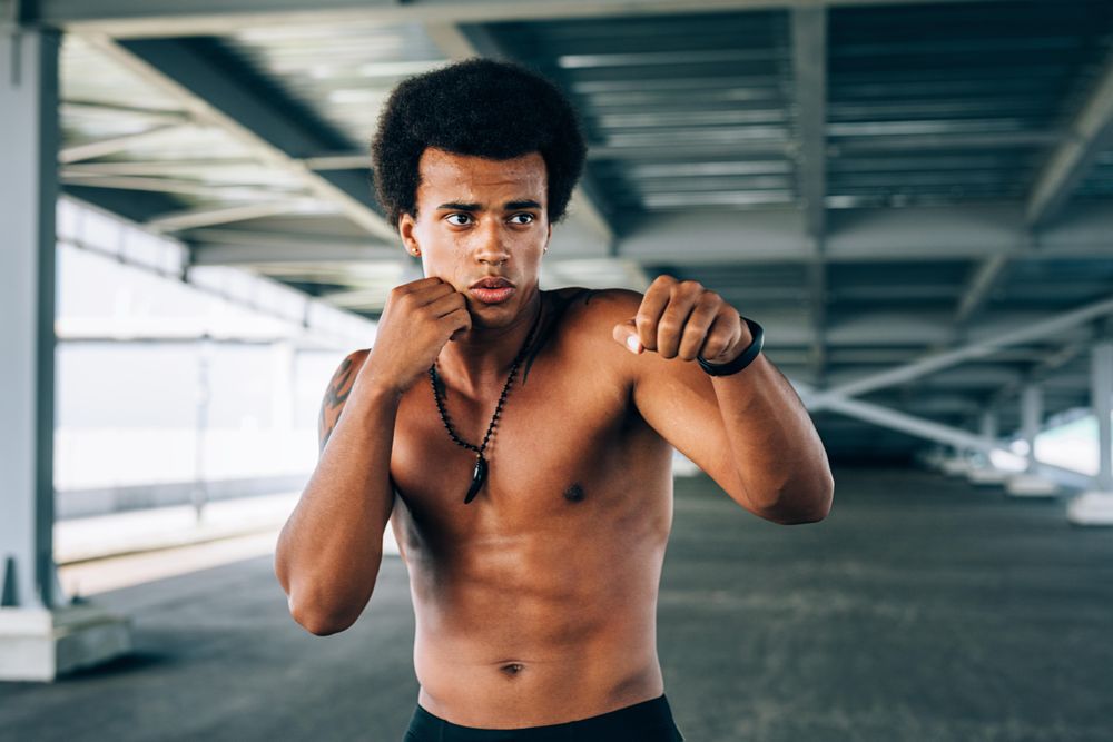 Black male athlete doing boxing training under a bridge