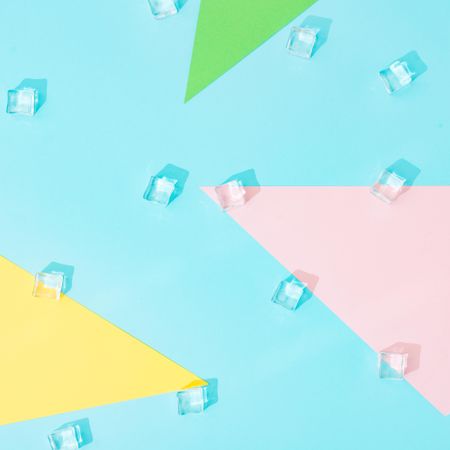 Creative summer background composition with ice cubes and colorful paper shapes