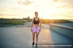 Muscular woman standing with the sunrise and city in the background 5r8glb