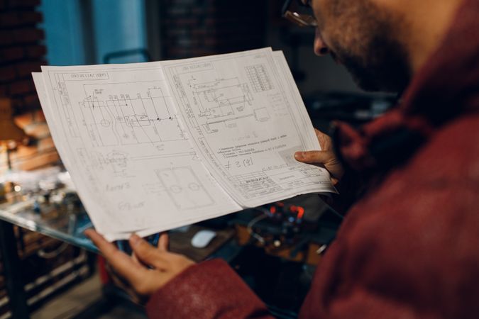 Back view of a man reading an engineering blueprint