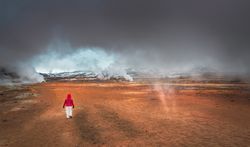 Traveler walking in valley near geysers