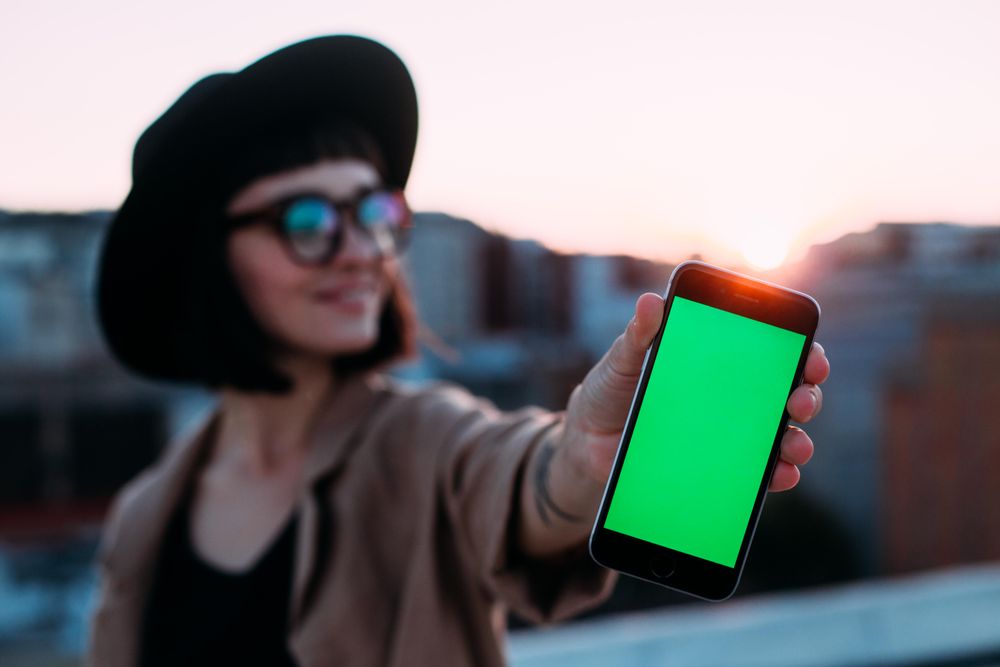 Woman with glasses and hat with smart phone outside