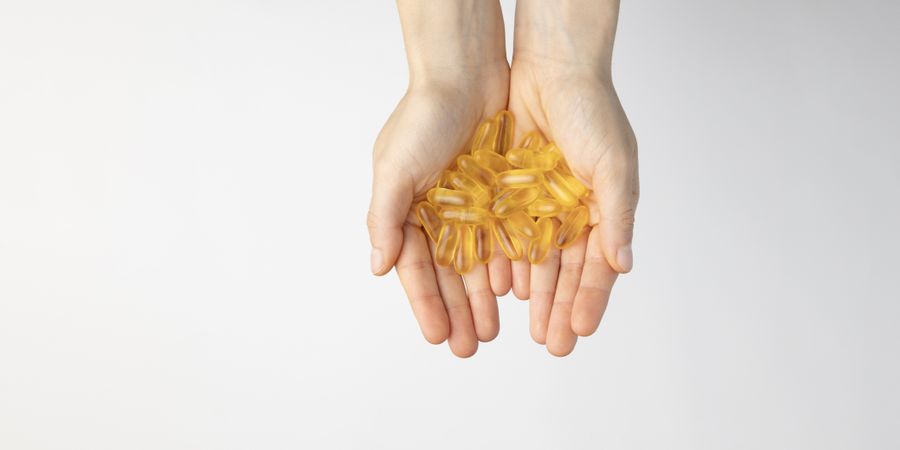 The hands of a woman hold a lot of oil capsules with omega 3, food supplement