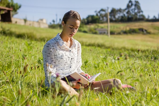 young student reading a book in the park