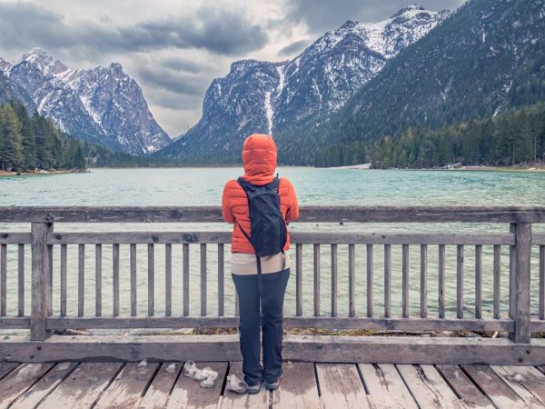 Anonymous traveler admiring mountains and lake from pier