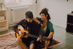 Cheerful couple playing guitar at home