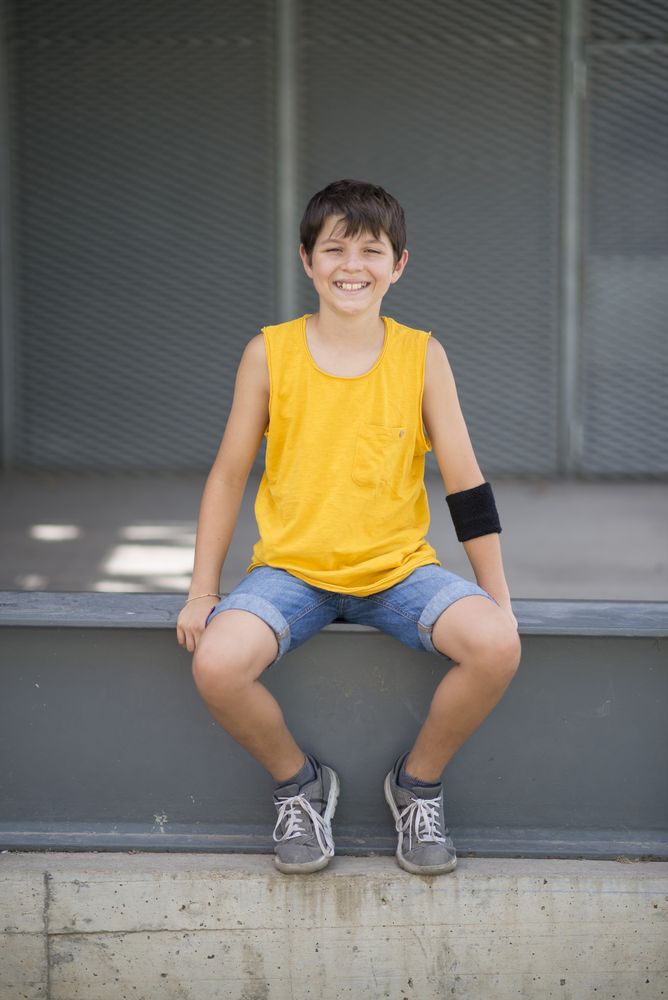 Casual dressed young smiling teen sitting outside, portrait