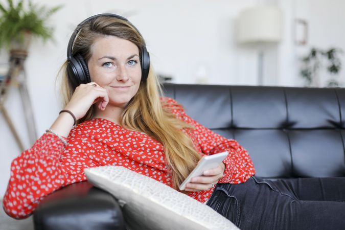 Smiling woman relaxing listening to music wearing headphones and using a smartphone