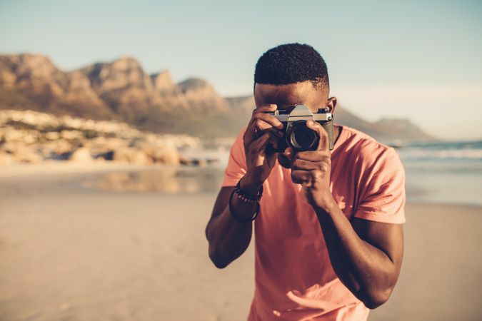 Portrait of man taking pictures with camera at the beach