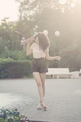Teenager with pink skateboard behind her head at sunset