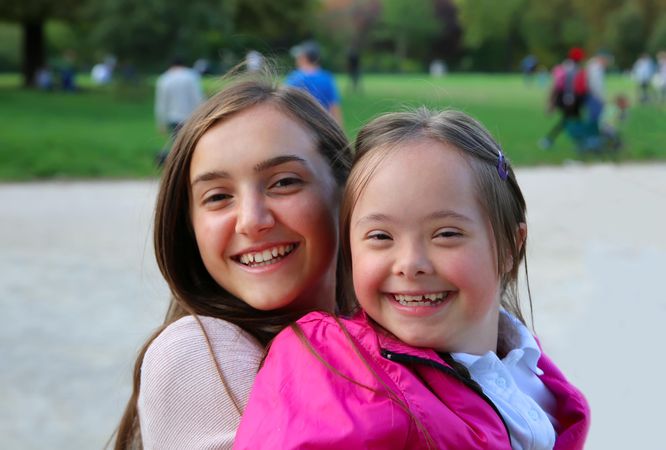 Two sisters smiling together in a public park