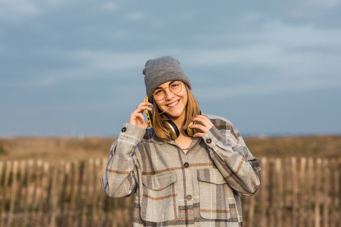 Anonymous smiling female talking on smartphone in nature