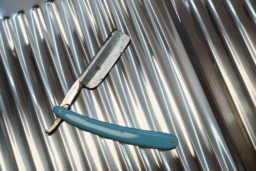 Vintage dangerous razor for haircuts on metal background