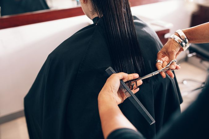 Rear view of female customer receiving hair trim at beauty salon