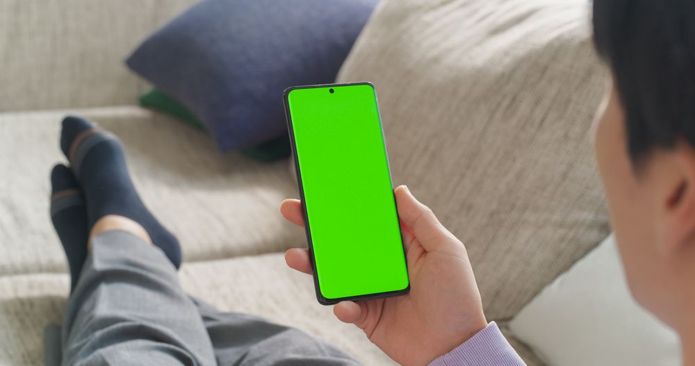 Over the Shoulder Footage of an Anonymous Male Relaxing at Home, Using Smartphone with Green Screen
