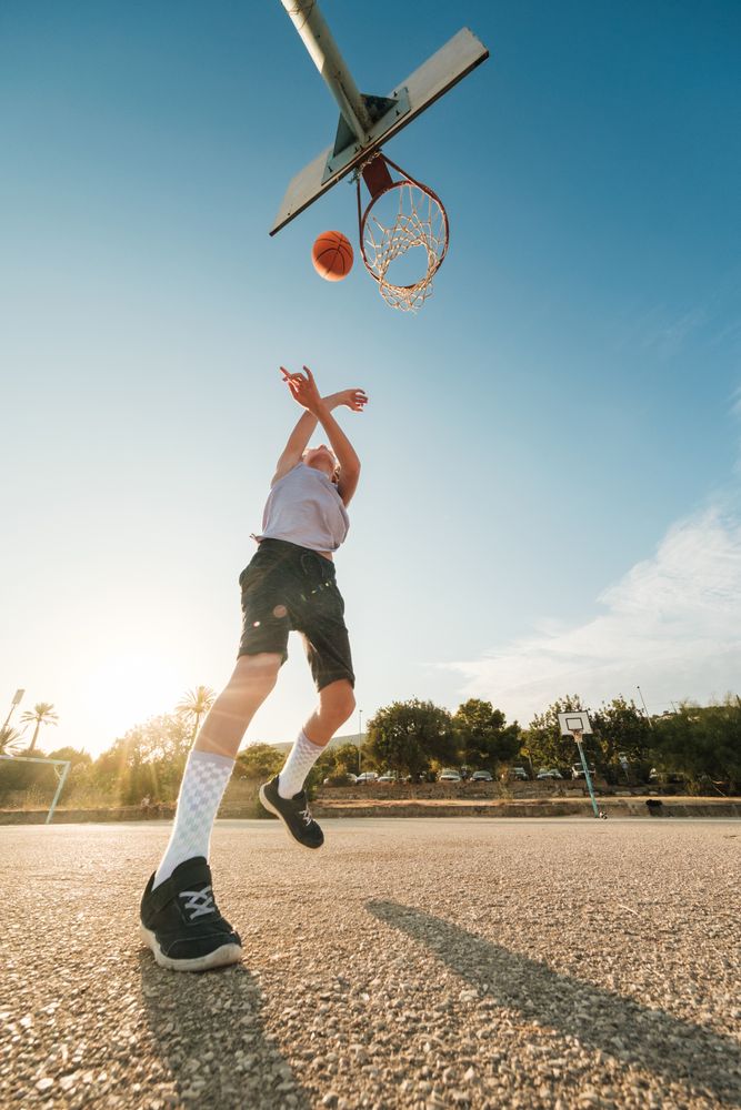 Boy throwing ball in hoop with hands raised
