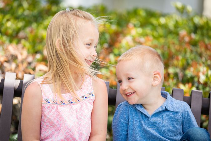 Young Sister and Brother Having Fun On The Bench At The Park