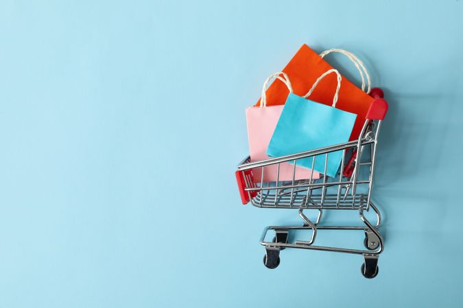 Shop cart with paper bags on blue background