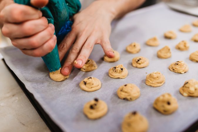 Crop baker squeezing dough on tray